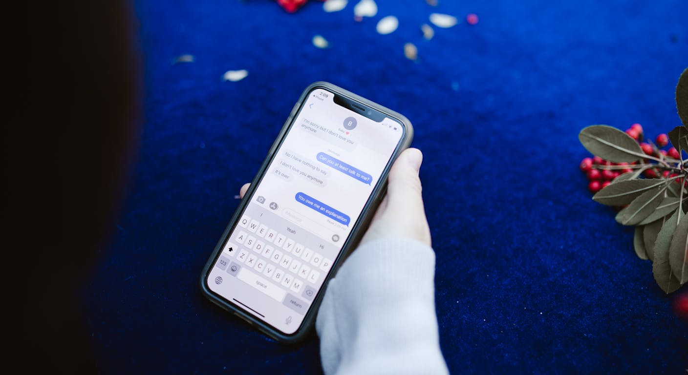 A hand holding a smartphone showing a chat conversation on screen.