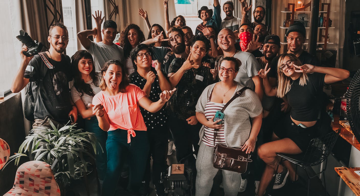 A diverse group of people making cheerful faces toward the camera.