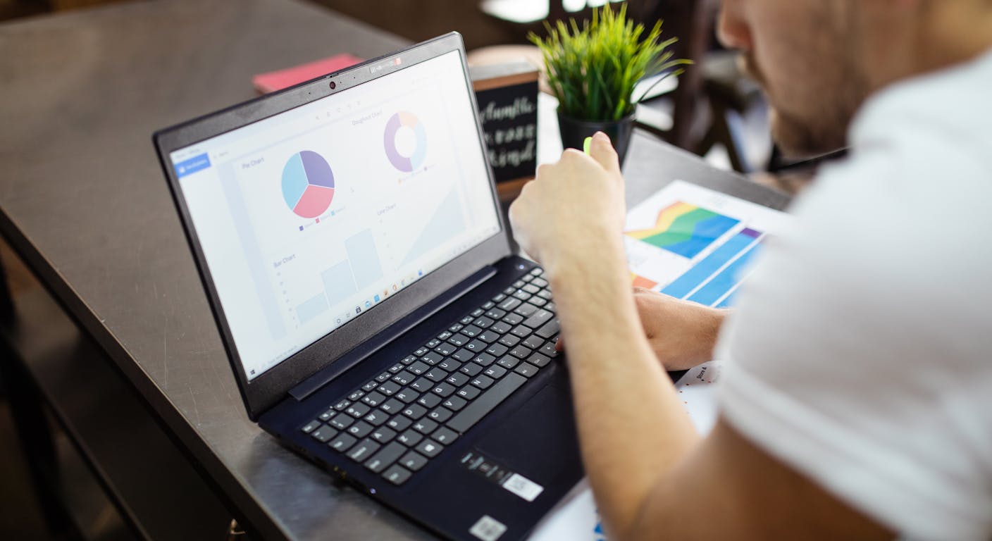 A person reviewing business charts and data on a laptop computer.